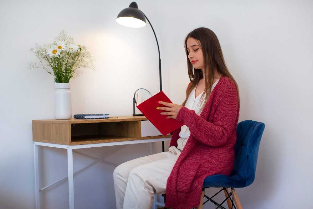 girl sitting on chair reading a book