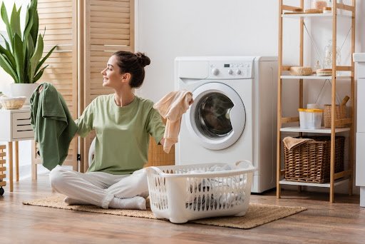 girl holding clothes infront of washing machine