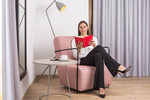Woman smiling while reading a book on a reading chair