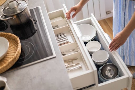 Woman organizing utensils in a drawer of a small kitchen