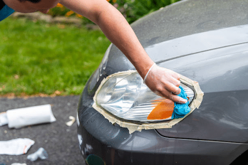 man cleaning headlight with toothpaste